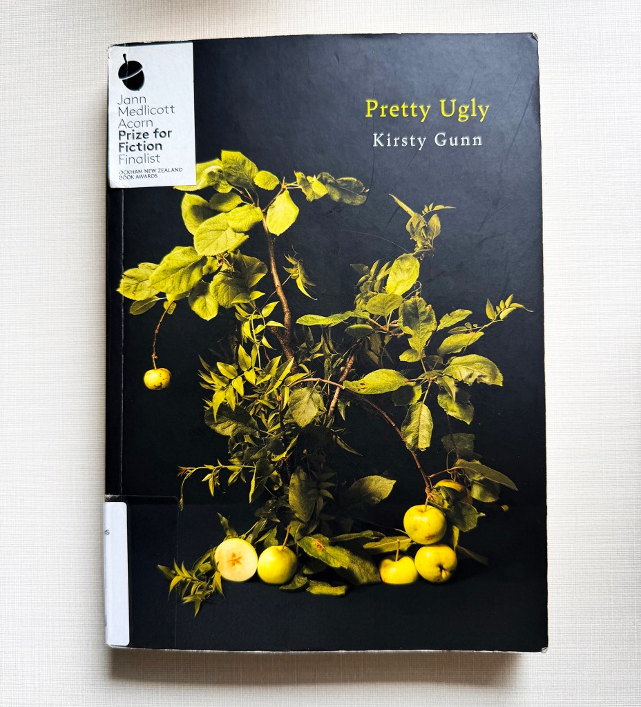 Book cover in black with a plant and fruit arrangement (green apples) as the design, Pretty Ugly by Kirsty Gunn.