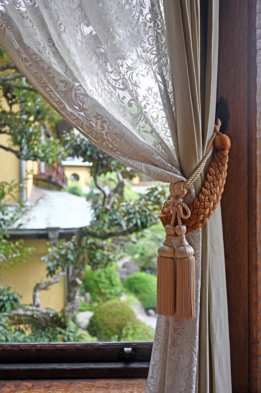 Old-timey curtain opened to show japanese garden outside