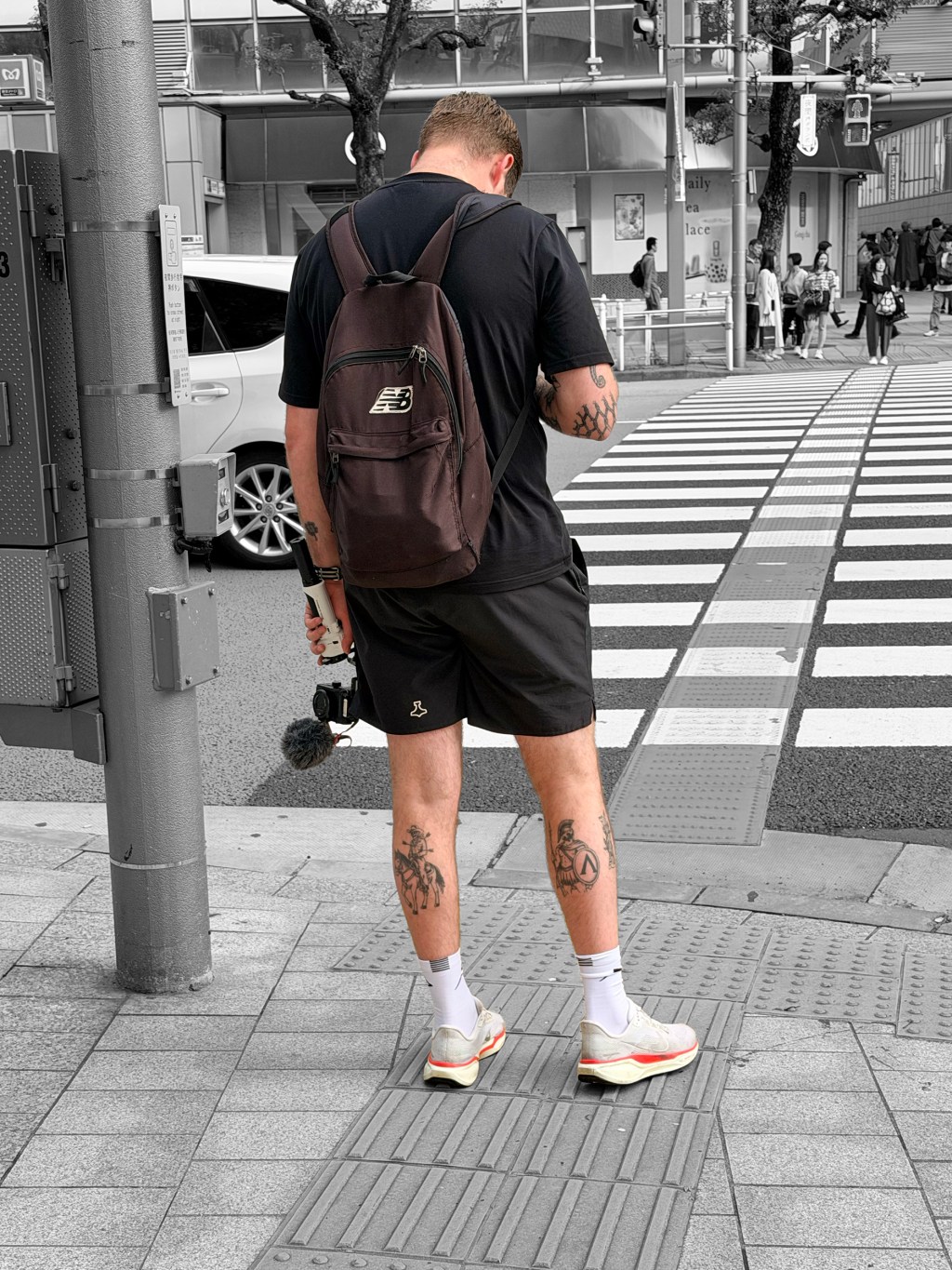 Caucasian guy looking at his phone while waiting for the light to turn green at a Tokyo crossing